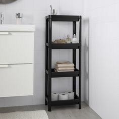 a bathroom with white tile and black shelving unit