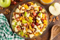 a bowl filled with fruit and nuts on top of a wooden table next to an apple