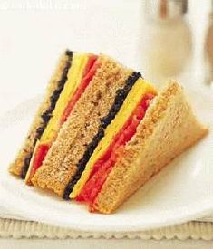 there is a sandwich on a white plate with red, yellow and black stripes in it