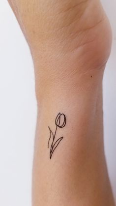 a small tattoo on the wrist of a woman's left arm with a single tulip