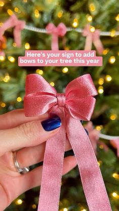 a person holding a pink ribbon with the words here's your sign to add bows to your tree this year