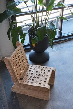 a wooden chair sitting next to a potted plant