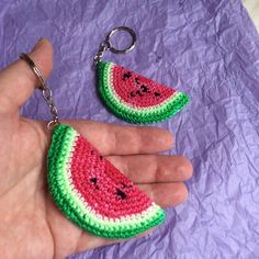 a hand holding two crocheted watermelon slices