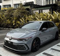 a grey car parked on the side of a road next to some bushes and trees