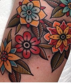 a close up of a person's arm with flowers and leaves tattooed on it