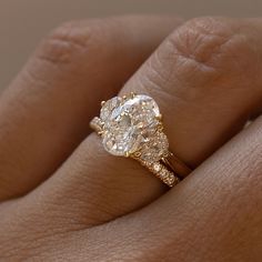 a woman's hand with a diamond ring on top of her finger and an engagement band