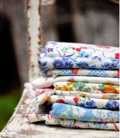 a stack of cloths sitting on top of a wooden bench