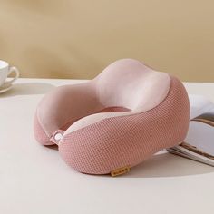 a pink pillow sitting on top of a table next to a cup and saucer