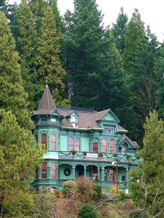 a large green house sitting on top of a lush green hillside next to tall trees