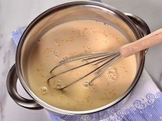 a metal pot filled with liquid and whisk on top of a blue towel