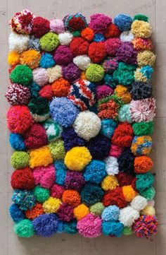 a multicolored wall hanging with pom - poms on the top and bottom