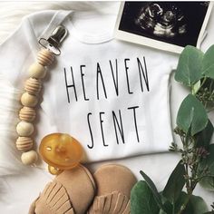 a white shirt with the words heaven sent on it next to some baby booties