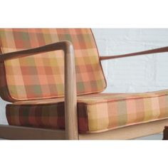 an orange and brown plaid chair sitting on top of a wooden frame