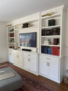 a living room with white bookcases and a large tv on top of it