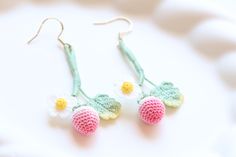 two crocheted flowers are hanging from the earwires of some kind of earrings