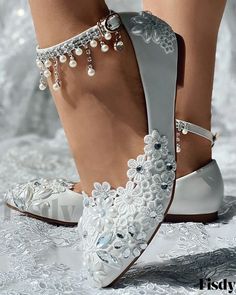 a woman's feet wearing white shoes with pearls on them