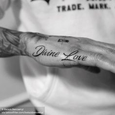 a tattooed hand with the words divine love written on it