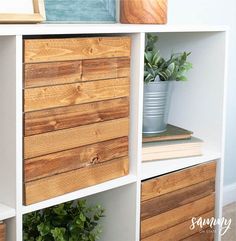 a white bookcase with wooden drawers and plants on top in the corner, next to a potted plant