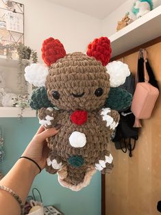 a person holding up a crocheted stuffed animal with horns and flowers on it's head