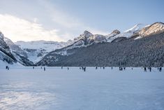 many people are skiing in the snow near mountains