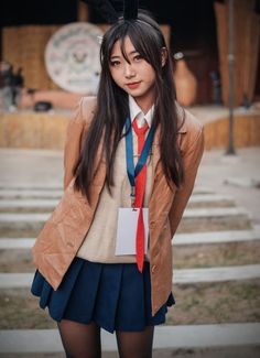 a girl with long black hair wearing a brown jacket and blue skirt is posing for the camera