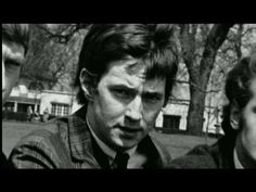 black and white photograph of two men in front of trees, one looking at the camera