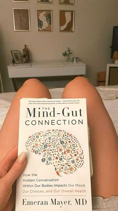 someone is reading a book about mind - gut connection on the bed in their bedroom