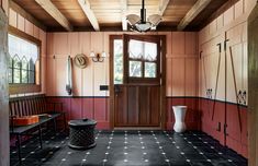 a room with red walls, black and white tile flooring and a wooden door