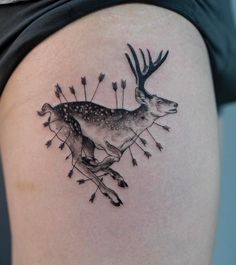 a deer tattoo on the side of a woman's thigh with arrows in it