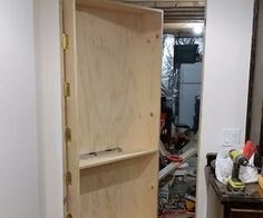 an open closet door in a room with tools and other items on the floor next to it