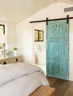 a bedroom with a bed, dresser and blue door in the wall next to it