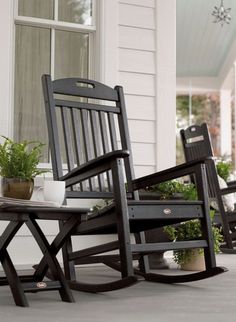 three rocking chairs sitting on the porch next to potted plants and a coffee table