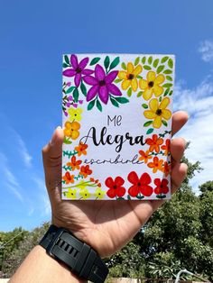 someone holding up a card with flowers on it that says, me alegra adventure