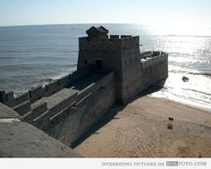 an old castle sitting on top of a beach next to the ocean