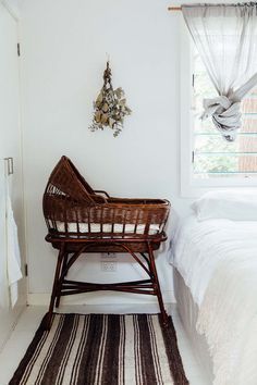 a bed room with a neatly made bed and a wicker chair next to it