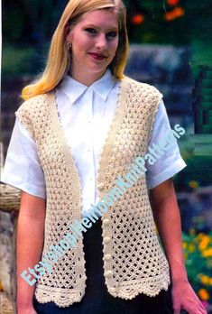 a woman wearing a white shirt and black skirt with a crocheted vest over her shoulders