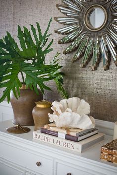 a table topped with books and vases next to a wall mounted sunburst