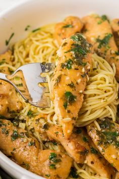 a white bowl filled with pasta and chicken covered in parmesan cheese, garnished with herbs