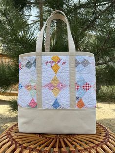 This one-of-a-kind tote showcases the artistry of a vintage quilt sourced from Gardnerville, Nevada. Each tote is a piece of heritage, lovingly remade to stand the test of time. Constructed from sturdy canvas, this tote will be your faithful companion for years to come, whether you're strolling through the local farmer's market or running errands in town. Embrace the spirit of this unique piece of functional and fashionable art, a testament to craftsmanship and history combined into a single, stylish accessory.  Features include:  * Fully lined with 15 oz. natural canvas  * Reinforced bottom  * Internal divided pocket * Approximately 15"w x 13"h x 5"d Quilt pattern:  * The Kite - Nancy Cabot, The Chicago Daily Tribune 1933 Discover the perfect companion to this one-of-a-kind tote with an o Vintage Tote Shoulder Bag With Detachable Strap, Multicolor Canvas Tote Satchel, Everyday Patchwork Tote Shoulder Bag, Gardnerville Nevada, Vintage Tapestry Tote Bag, Multicolor Patchwork Tote Satchel, Reno Nv, Vintage Quilt, Heritage Collection