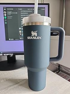 a coffee cup sitting next to a computer monitor