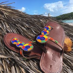 Beaded in the Maasai tradition by women Artisans receiving a fair wage, our sandals beautiful but tough - well-suited for everyday wear. Made by hand in Tanzania, each pair will have slight variations adding to its unique style. 100% of net proceeds are invested the Artisans and our innovative menstrual hygiene program, UhuruPads (East Africa's first 100% compostable sanitary pad, produced by a team of women for distribution to girls keeping them in school). Product Features: beautiful beading t Traditional Brown Toe Post Flip Flops, Traditional T-strap Sandals With Single Toe Strap For Vacation, Traditional Closed Toe Barefoot Sandals For Vacation, Traditional T-strap Sandals For Vacation, Traditional Handmade Brown Flip Flops, Traditional Toe Loop Sandals For Vacation, Traditional Adjustable Brown Flip Flops, Traditional Adjustable Toe Post Sandals, Traditional Closed Toe Barefoot Sandals For Beach