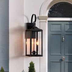 an outdoor light on the side of a house with potted plants in front of it