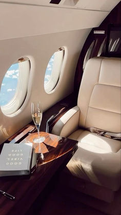 the interior of an airplane with two wine glasses and a book