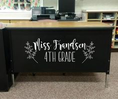 a desk with a sign that says miss frances 4th grade on it in the middle of a classroom