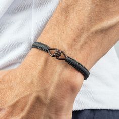 a man wearing a black leather bracelet with an open knot on it's wrist