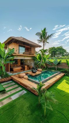 an outdoor swimming pool surrounded by lush green grass and palm trees in front of a house