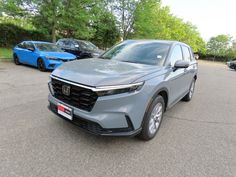 a gray honda suv is parked in a parking lot with other cars and trees behind it