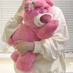 a woman holding a pink teddy bear in her arms