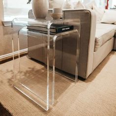 a living room with a couch, coffee table and vase on the end table in front of it