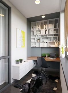 a room with a desk, chair and bookcases in the corner next to a window